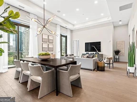 dining room with plenty of natural light, a tray ceiling, and light hardwood / wood-style flooring