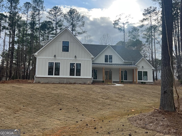 modern farmhouse style home with brick siding, board and batten siding, a porch, metal roof, and a standing seam roof