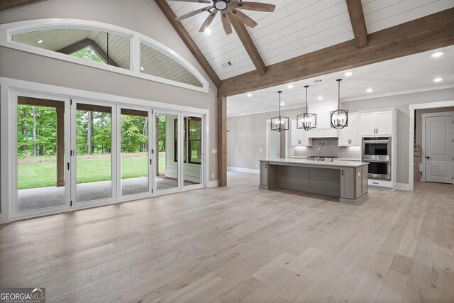 unfurnished living room with built in features, ceiling fan, high vaulted ceiling, a fireplace, and light hardwood / wood-style floors