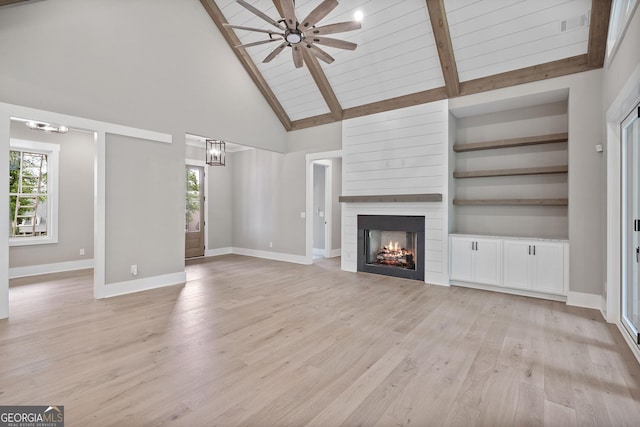 unfurnished living room featuring baseboards, light wood-type flooring, ceiling fan with notable chandelier, a fireplace, and high vaulted ceiling