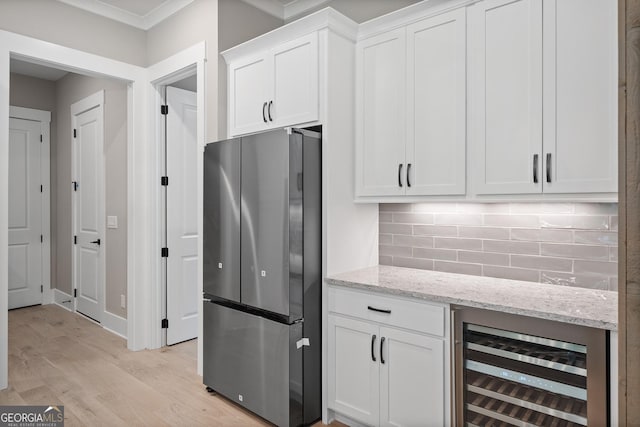 kitchen with tasteful backsplash, light stone countertops, beverage cooler, freestanding refrigerator, and white cabinets