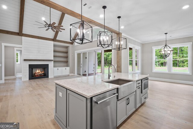 kitchen with light wood finished floors, vaulted ceiling with beams, gray cabinetry, a sink, and dishwasher