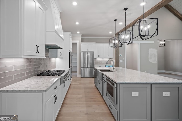 kitchen with light wood-type flooring, a large island with sink, white cabinets, stainless steel appliances, and a sink