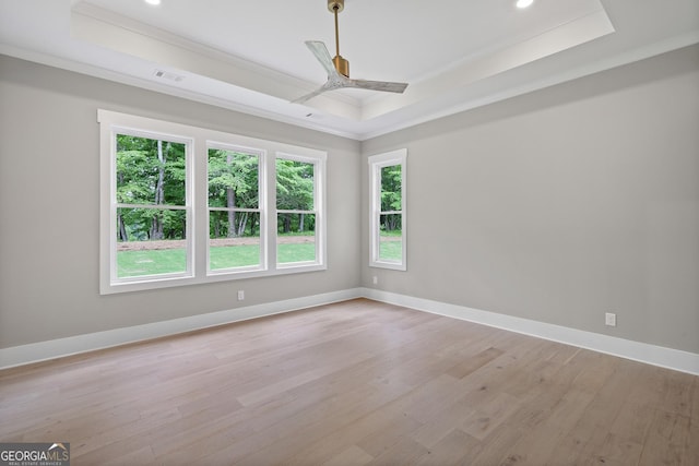 empty room with a tray ceiling, baseboards, visible vents, and light wood-style flooring