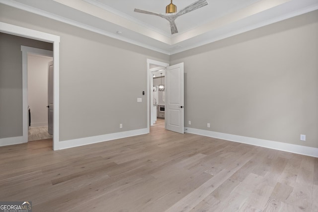 unfurnished bedroom with baseboards, light wood-style floors, a raised ceiling, and ornamental molding