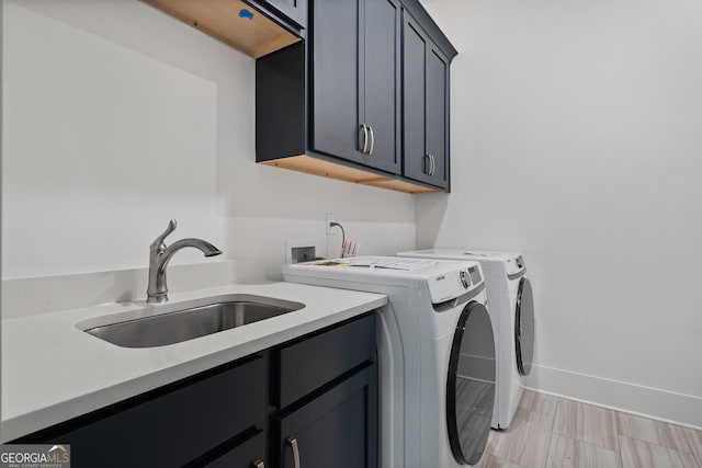 laundry area featuring a sink, baseboards, cabinet space, and washer and clothes dryer