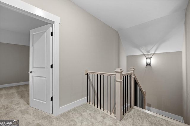 interior space featuring an upstairs landing, baseboards, lofted ceiling, and carpet