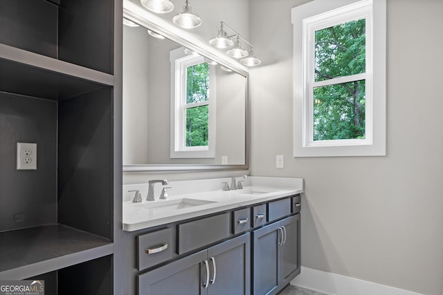 bathroom featuring double vanity, baseboards, and a sink