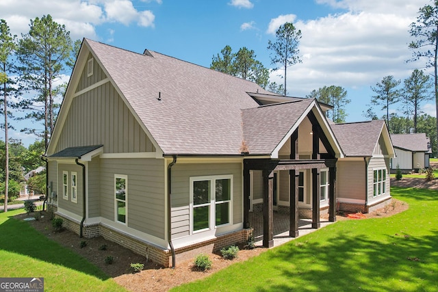 back of house with a yard, a patio area, board and batten siding, and a shingled roof