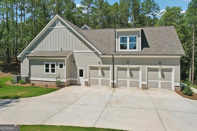 view of front facade with central air condition unit, brick siding, board and batten siding, and a shingled roof