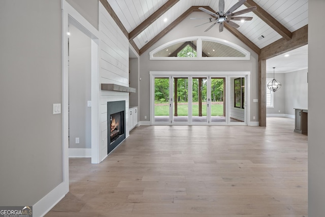 unfurnished living room with beam ceiling, high vaulted ceiling, ceiling fan with notable chandelier, a fireplace, and light wood finished floors