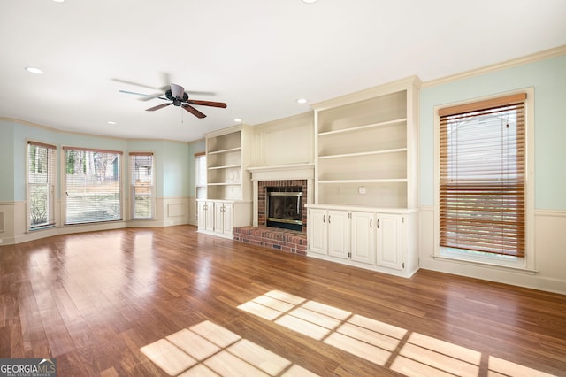 unfurnished living room with light hardwood / wood-style flooring, built in features, ceiling fan, a fireplace, and ornamental molding