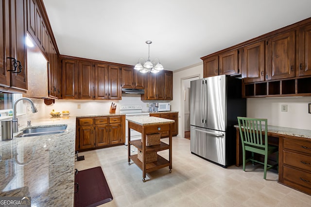 kitchen featuring built in desk, pendant lighting, sink, light stone countertops, and white appliances