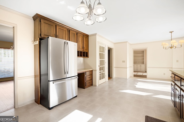 kitchen featuring pendant lighting, stainless steel refrigerator, ornamental molding, an inviting chandelier, and built in shelves