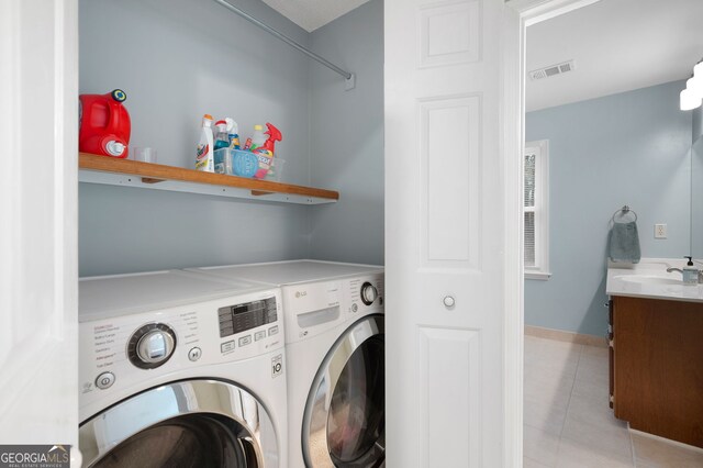 washroom with sink, washer and dryer, and light tile patterned floors