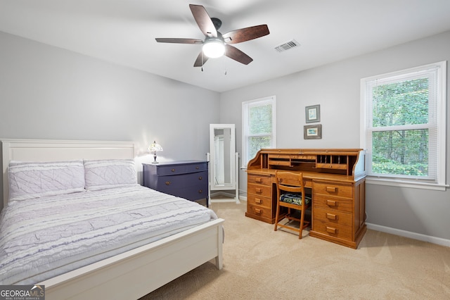 bedroom with multiple windows, ceiling fan, and light carpet