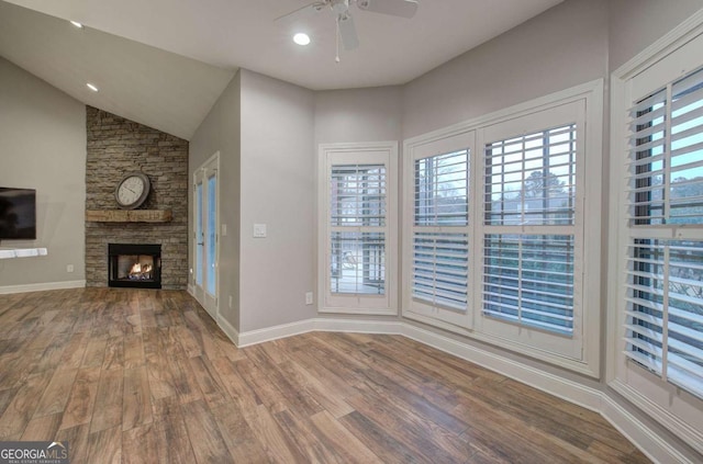 unfurnished living room featuring wood-type flooring, a stone fireplace, and ceiling fan