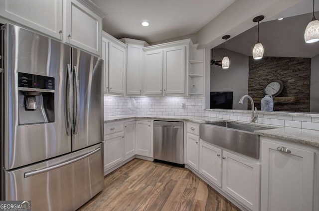 kitchen with stainless steel appliances, sink, white cabinets, and decorative light fixtures