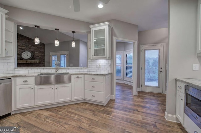 kitchen with sink, backsplash, stainless steel appliances, white cabinets, and vaulted ceiling