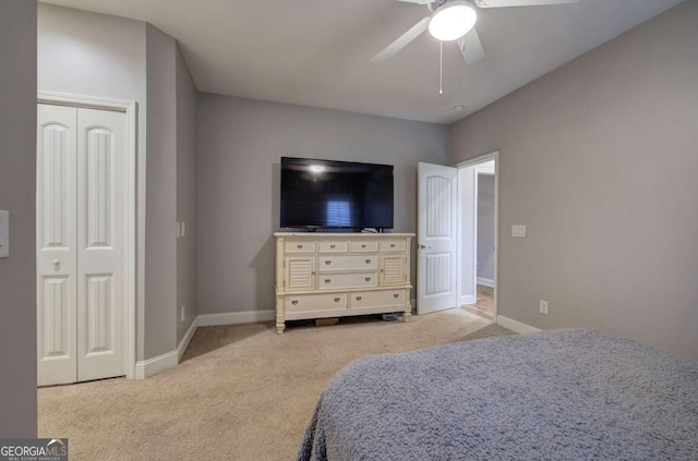 bedroom with light colored carpet, ceiling fan, and a closet