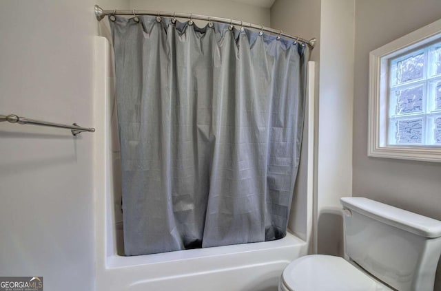 bathroom featuring shower / bathtub combination with curtain and toilet