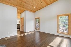 spare room featuring dark wood-type flooring, wooden ceiling, and high vaulted ceiling