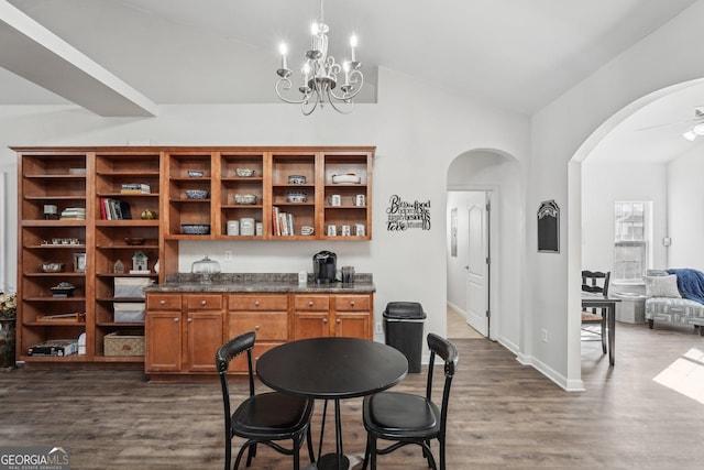 dining area featuring dark wood-type flooring, lofted ceiling, and ceiling fan with notable chandelier