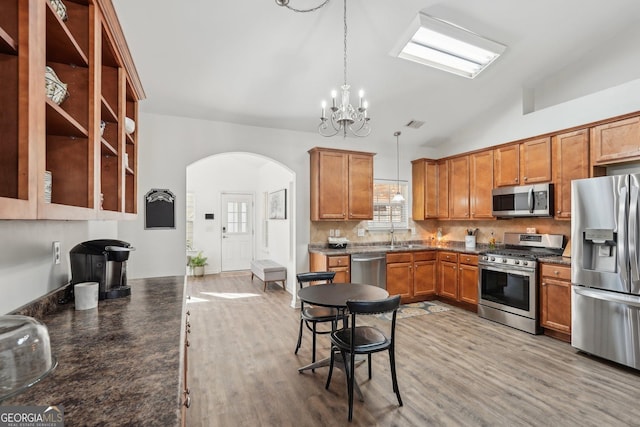 kitchen with a wealth of natural light, appliances with stainless steel finishes, pendant lighting, and backsplash