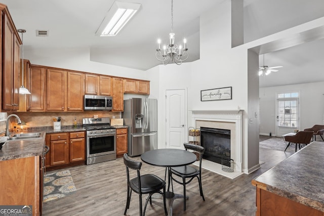 kitchen featuring ceiling fan with notable chandelier, pendant lighting, sink, stainless steel appliances, and dark wood-type flooring