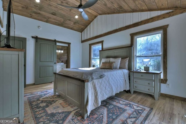 bedroom featuring lofted ceiling, ceiling fan, wood ceiling, a barn door, and light hardwood / wood-style flooring