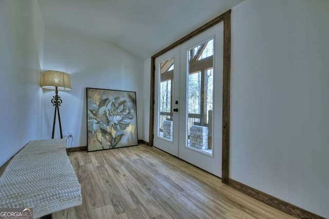 doorway to outside featuring lofted ceiling, light hardwood / wood-style flooring, and french doors