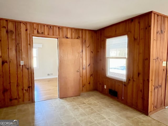 empty room with plenty of natural light and wood walls