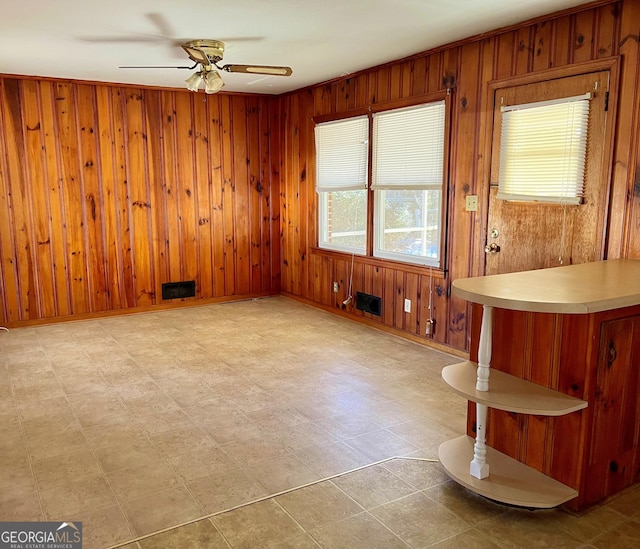 unfurnished room featuring ceiling fan and wood walls