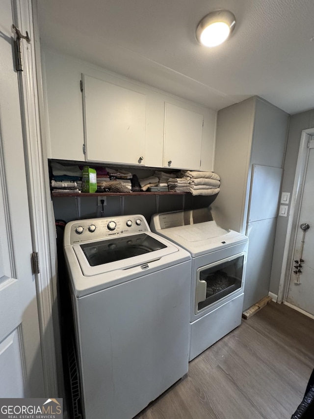 clothes washing area featuring independent washer and dryer, cabinets, a textured ceiling, and light wood-type flooring