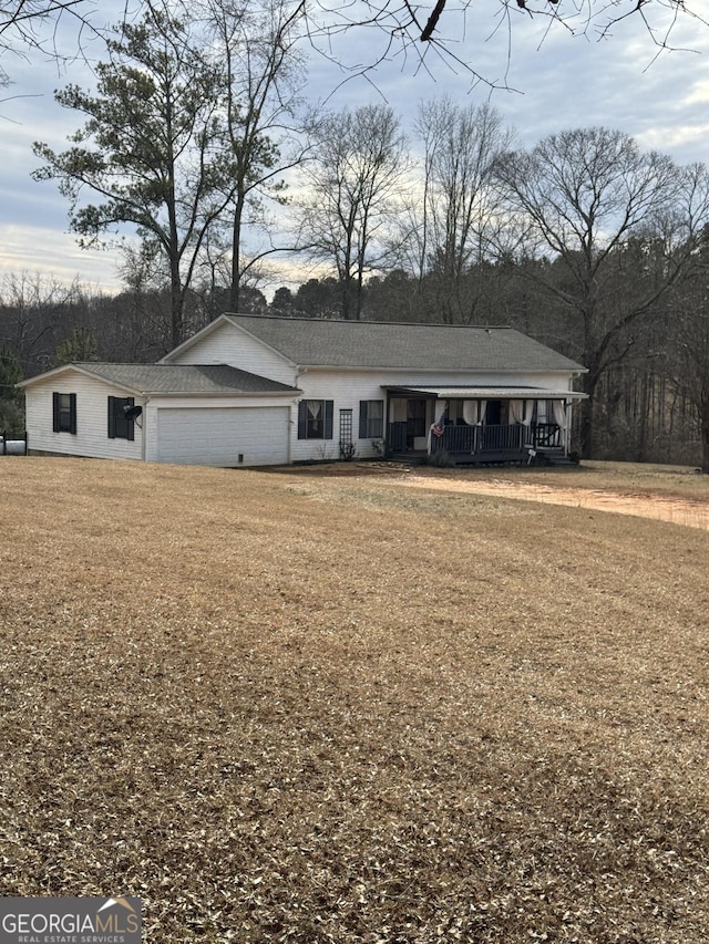 view of front of property featuring a garage, a front lawn, and covered porch