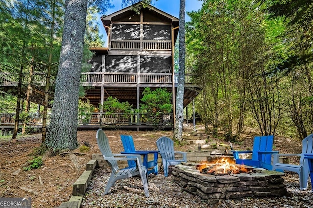 back of property featuring a sunroom and an outdoor fire pit