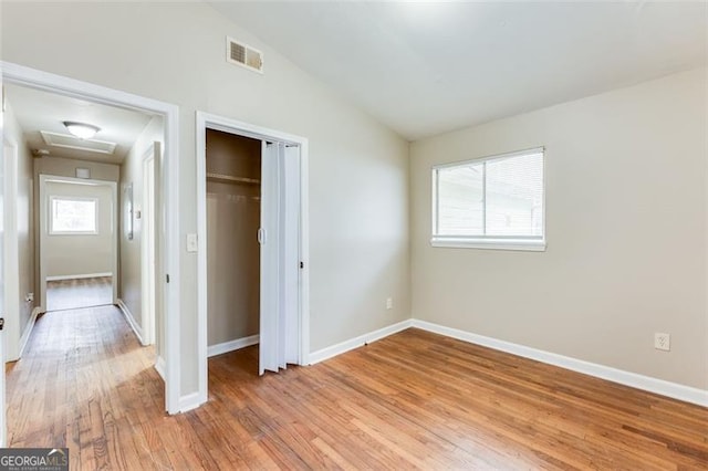 unfurnished bedroom featuring wood-type flooring, lofted ceiling, and a closet