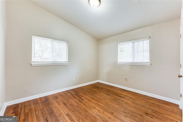 empty room with hardwood / wood-style flooring and vaulted ceiling