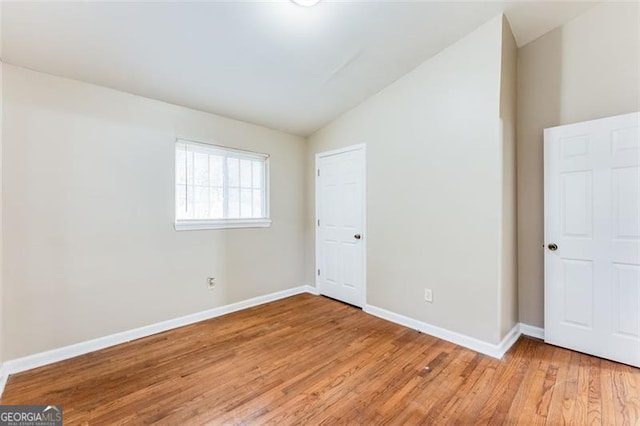 unfurnished bedroom with lofted ceiling and light wood-type flooring