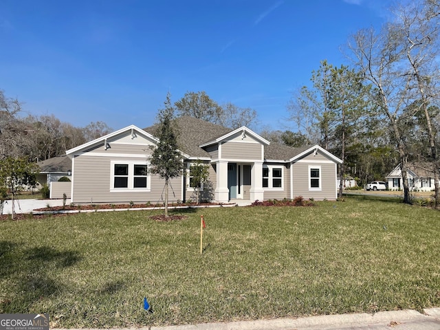 view of front of house with a shingled roof and a front yard