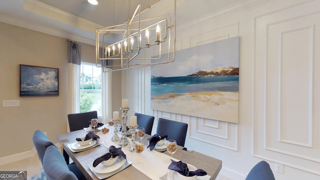 dining space with baseboards, ornamental molding, a raised ceiling, and a chandelier