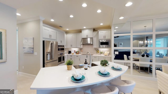 kitchen featuring sink, appliances with stainless steel finishes, hanging light fixtures, white cabinets, and a kitchen bar