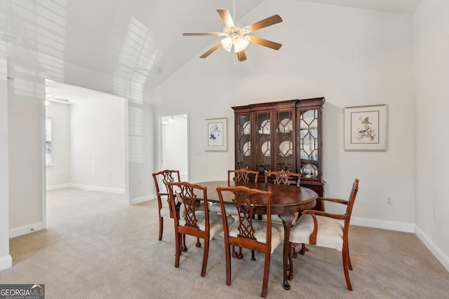 carpeted dining area with ceiling fan and high vaulted ceiling