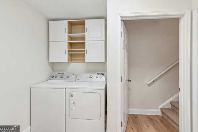 clothes washing area featuring cabinets, washing machine and dryer, and light hardwood / wood-style flooring