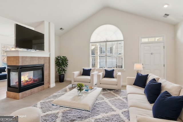 carpeted living room with lofted ceiling and a tile fireplace