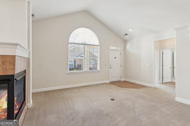 unfurnished living room with a tiled fireplace, light colored carpet, and lofted ceiling