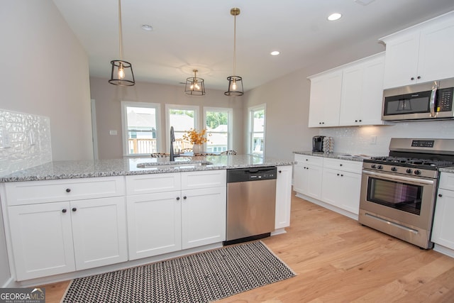 69 Oakhurst Trl, Sharpsburg, GA 30277 - kitchen with stainless steel appliances, light wood-style floors, white cabinets, backsplash, and pendant lighting