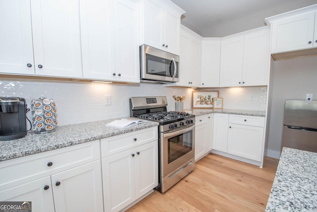 69 Oakhurst Trl, Sharpsburg, GA 30277 - kitchen with stainless steel appliances, light wood finished floors, decorative backsplash, white cabinetry, and light stone counters