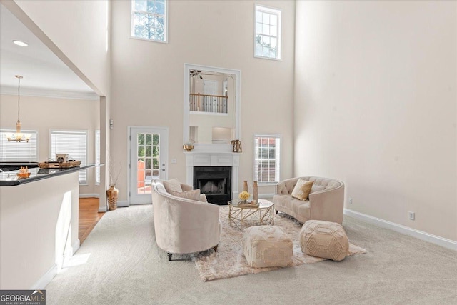 living room with crown molding, a towering ceiling, a chandelier, and light carpet