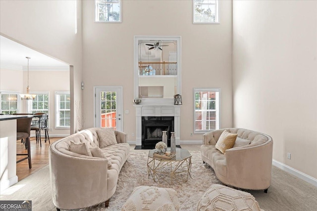 living room with an inviting chandelier, a towering ceiling, crown molding, and a healthy amount of sunlight